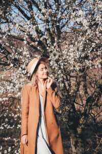 a girl standing beside a cherry blossom tree