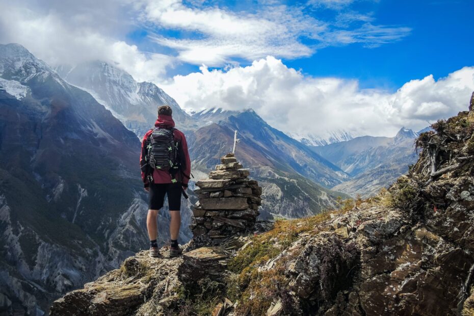 a travelling guy standing at the top of a mountain viewing the other side of the mountain